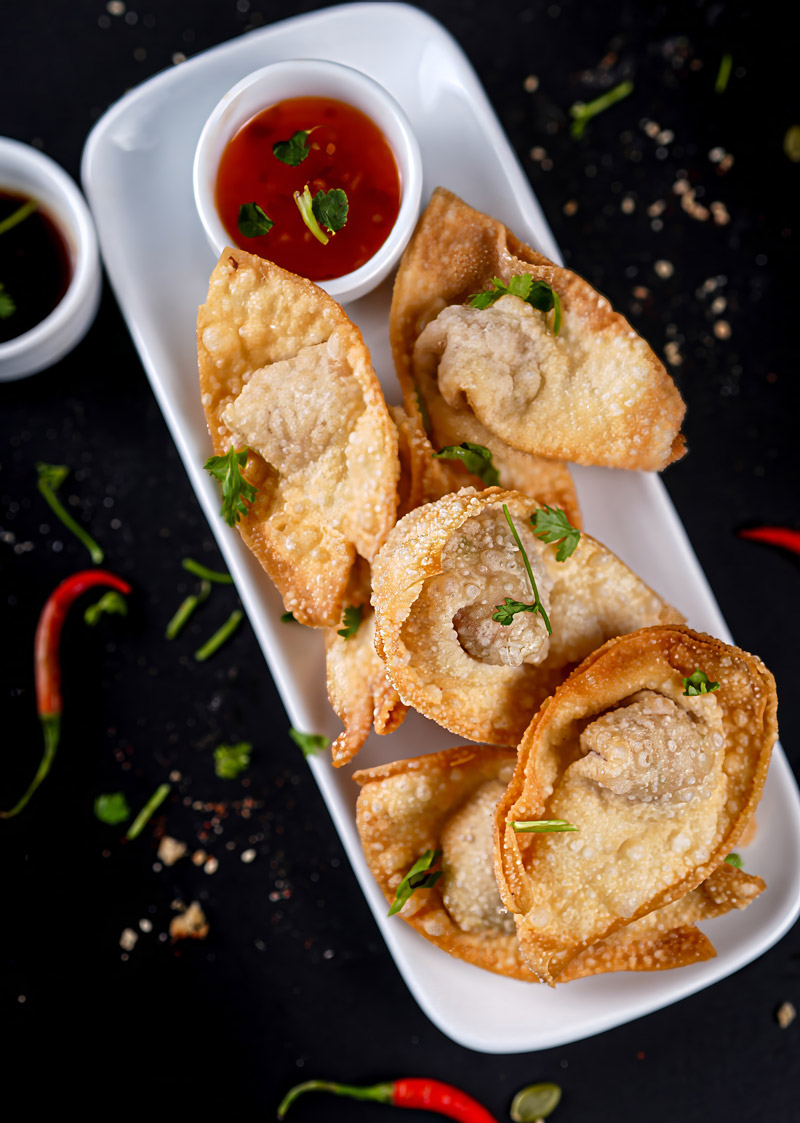 Crispy shrimp wontons garnished with fresh herbs and served with sauce.