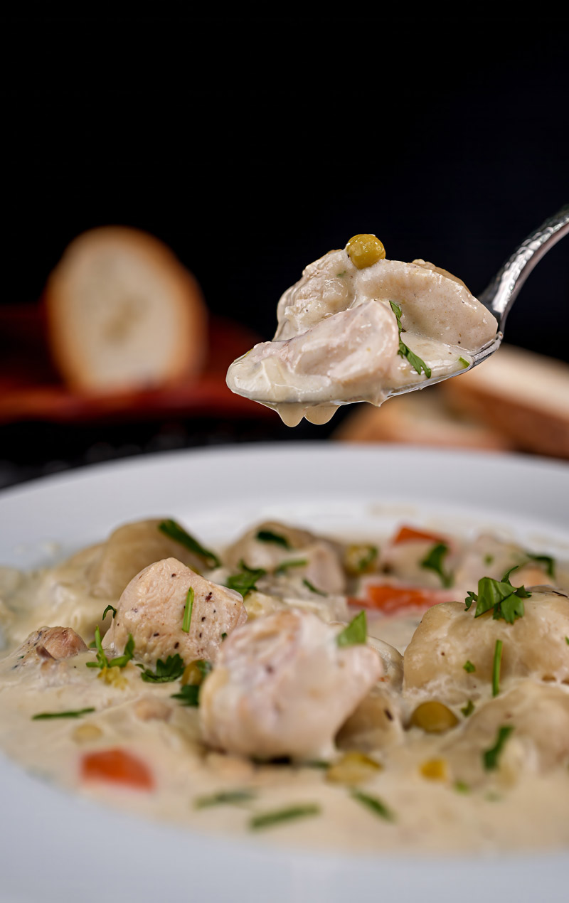 Spoonful of creamy chicken stew with a dumpling, showcasing the rich texture and flavors.