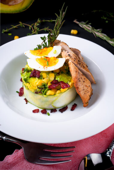 Beautifully presented avocado chicken salad with corn, eggs and sliced chicken breast