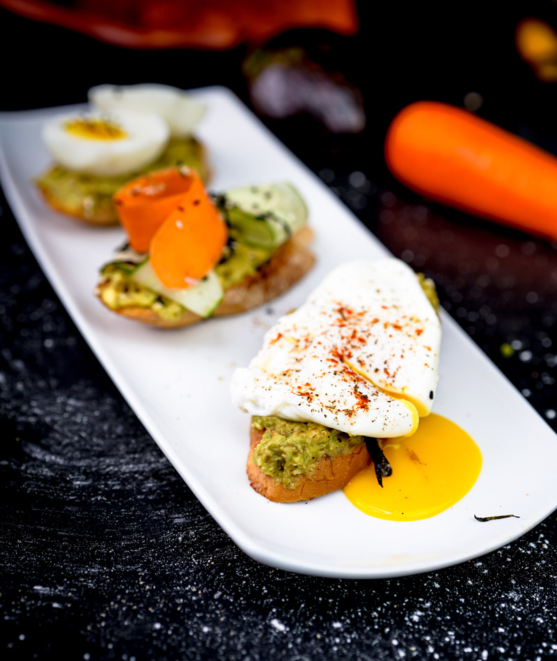 Avocado toast flight featuring poached egg and vegetable toppings