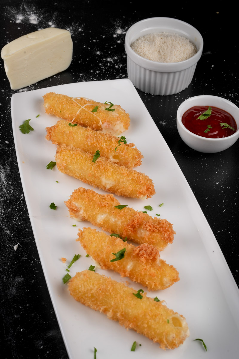 Breaded mozzarella sticks on plate with parmesan coating visible