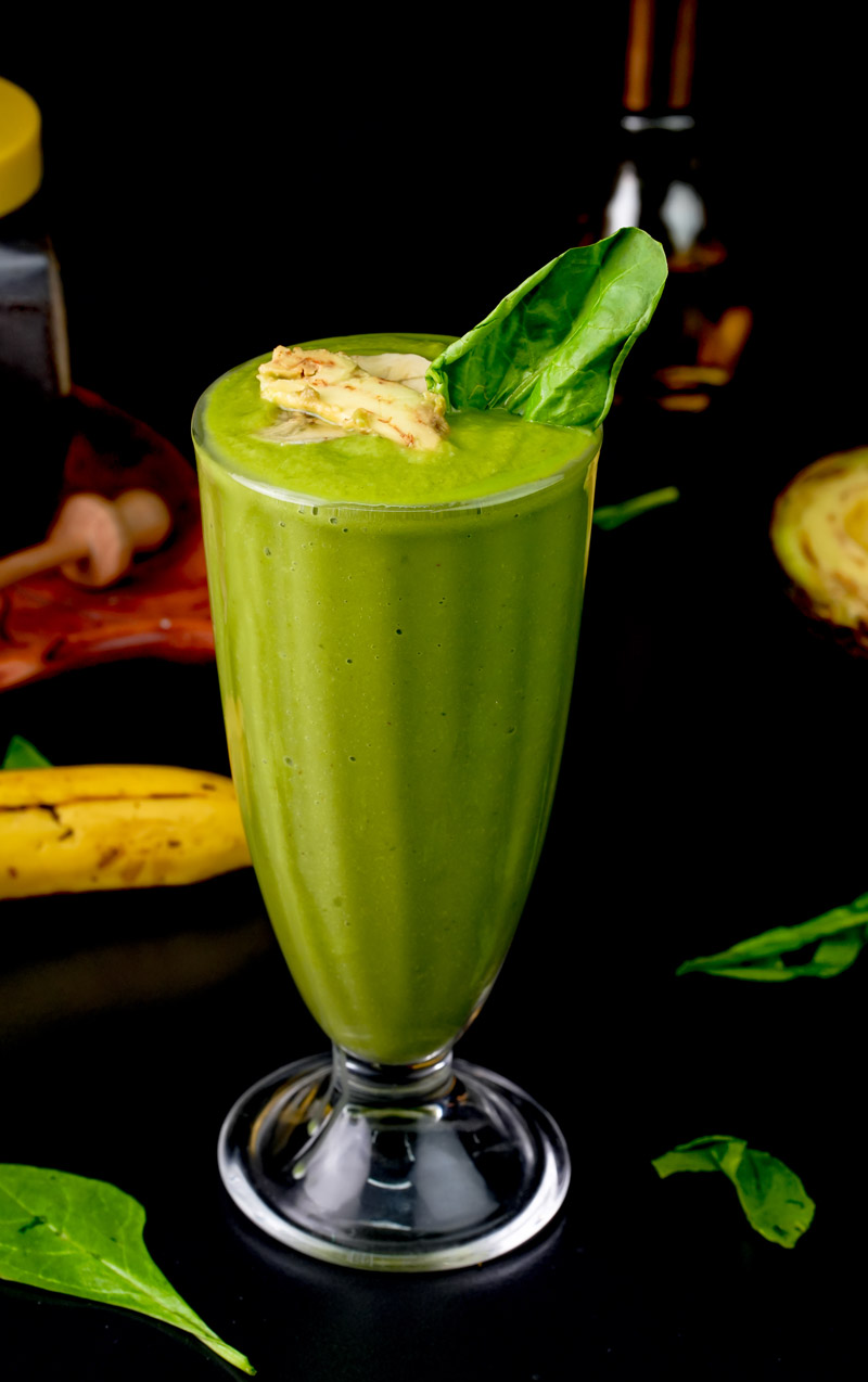 Bright green avocado spinach smoothie with spinach leaf garnish