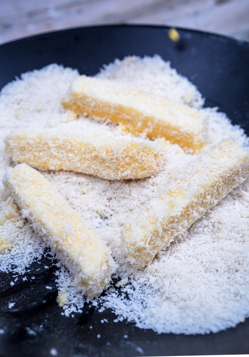 Cheese sticks being coated in breadcrumbs during preparation