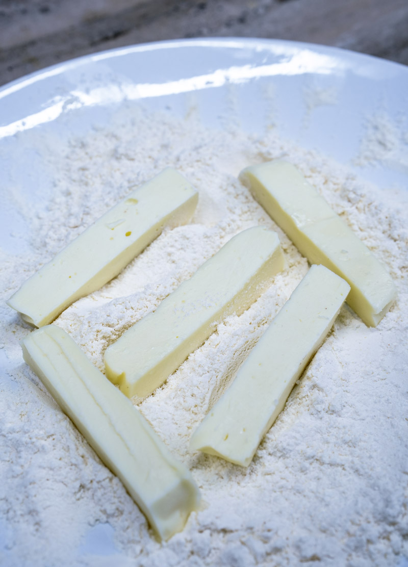 Cheese sticks preparation with sticks laid in flour mixture