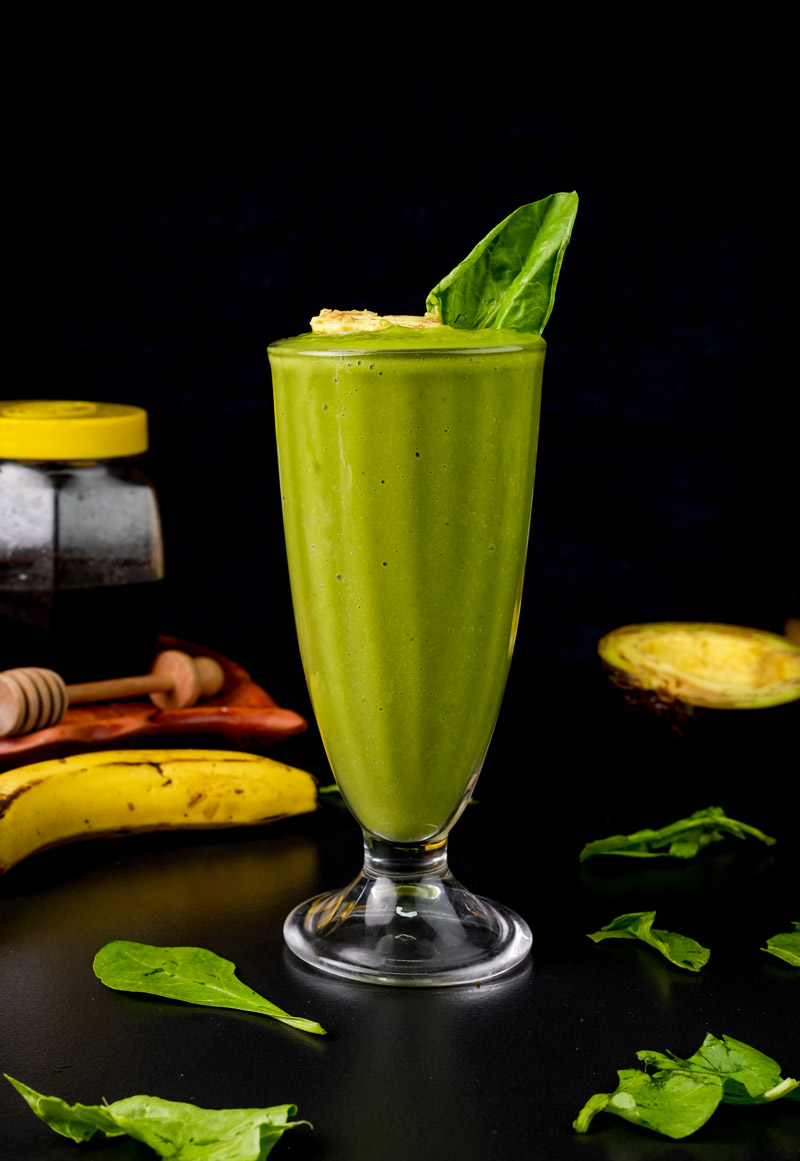 Fresh avocado banana smoothie with spinach leaf garnish