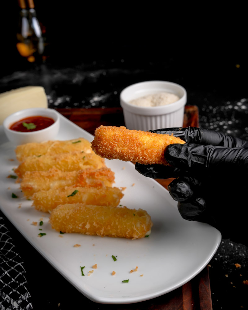 Golden fried mozzarella sticks on white plate with marinara dipping sauce