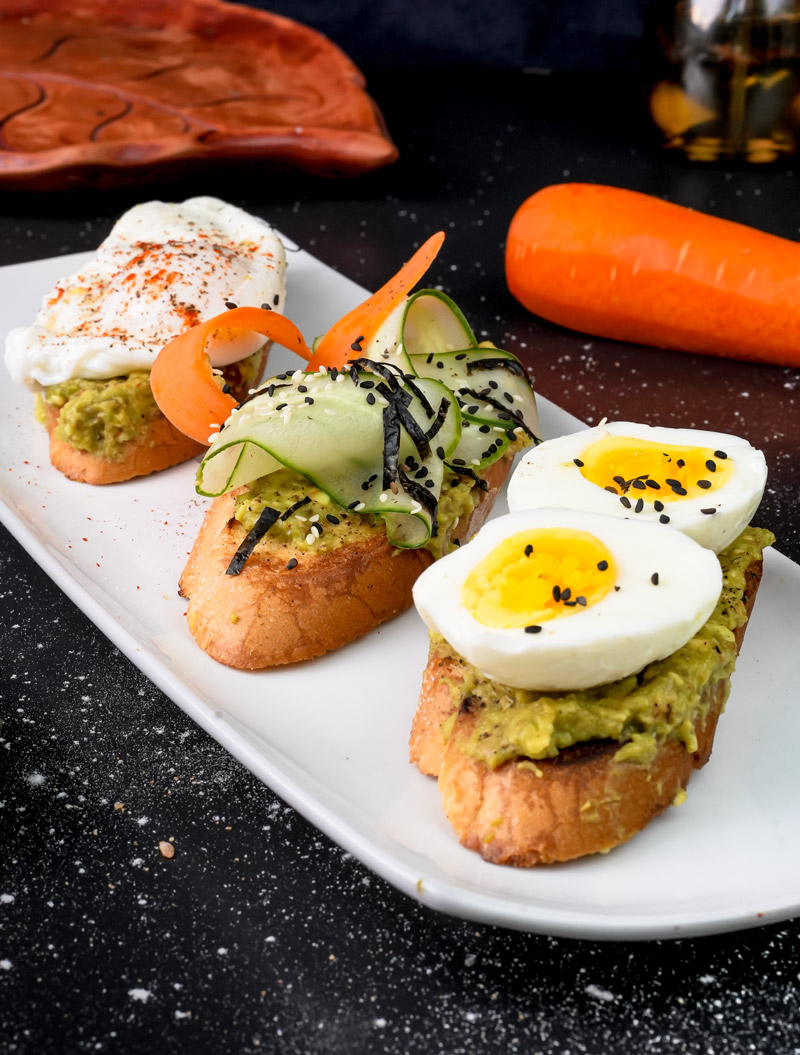 Homemade avocado toast trio with eggs and fresh vegetables
