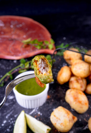 Close-up of seafood loitta fry fritter being dipped in green chutney