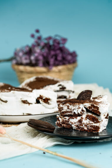 Oreo icebox cake with purple flowers in background on turquoise setting