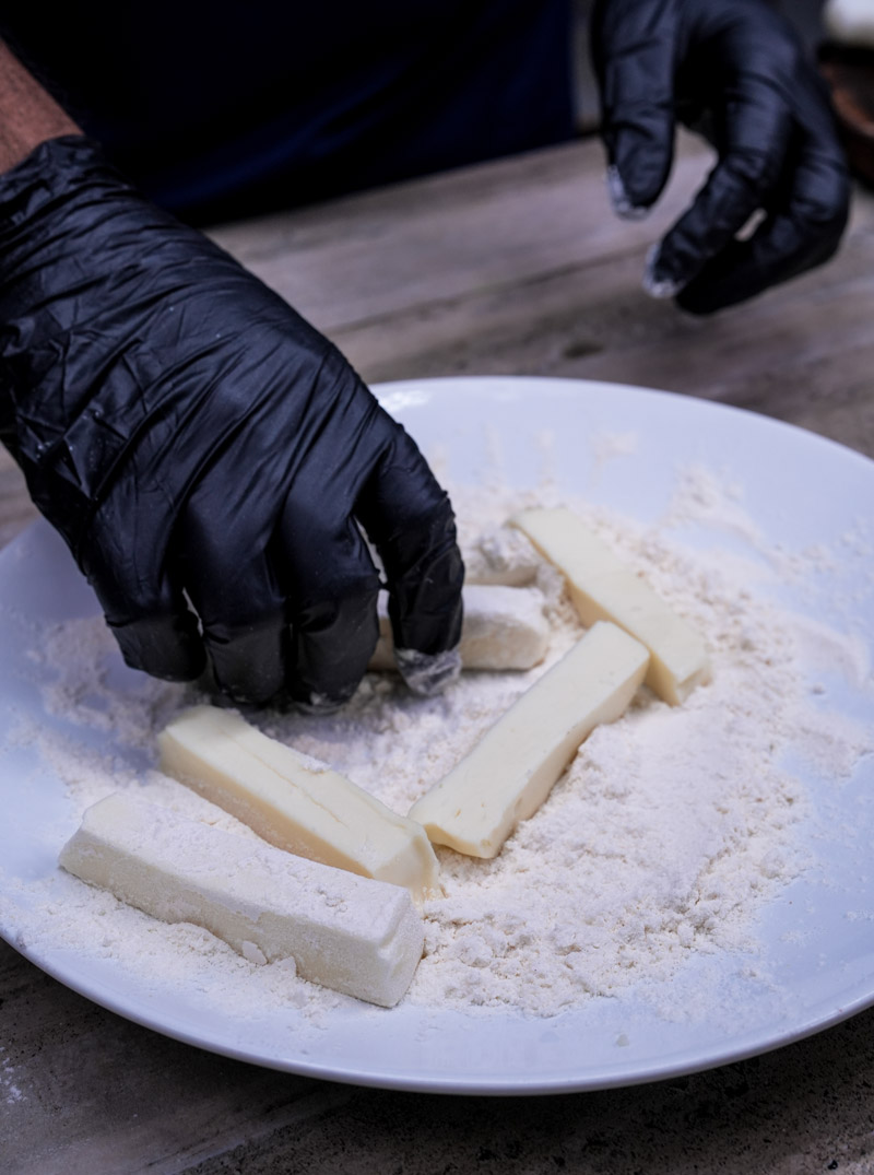 Preparing mozzarella sticks by coating cheese in flour mixture