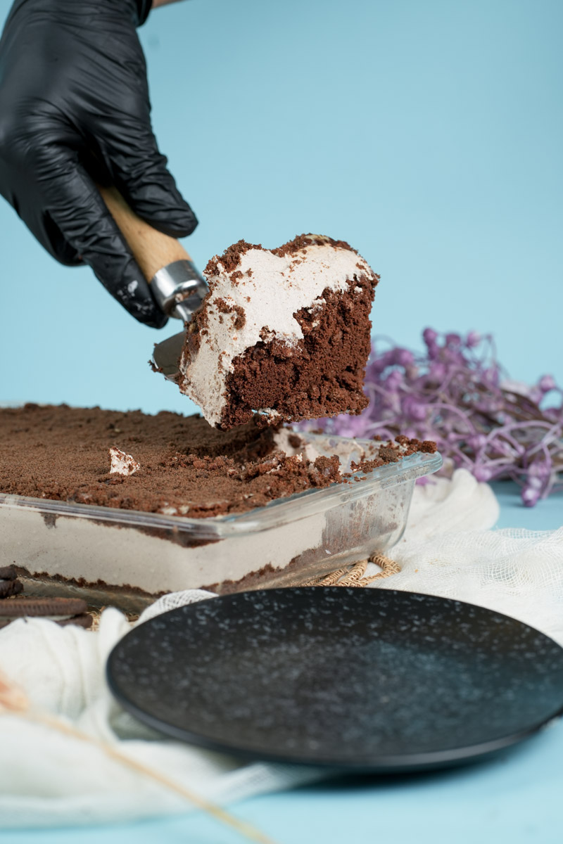 Serving Oreo dirt cake with spatula showing creamy layers