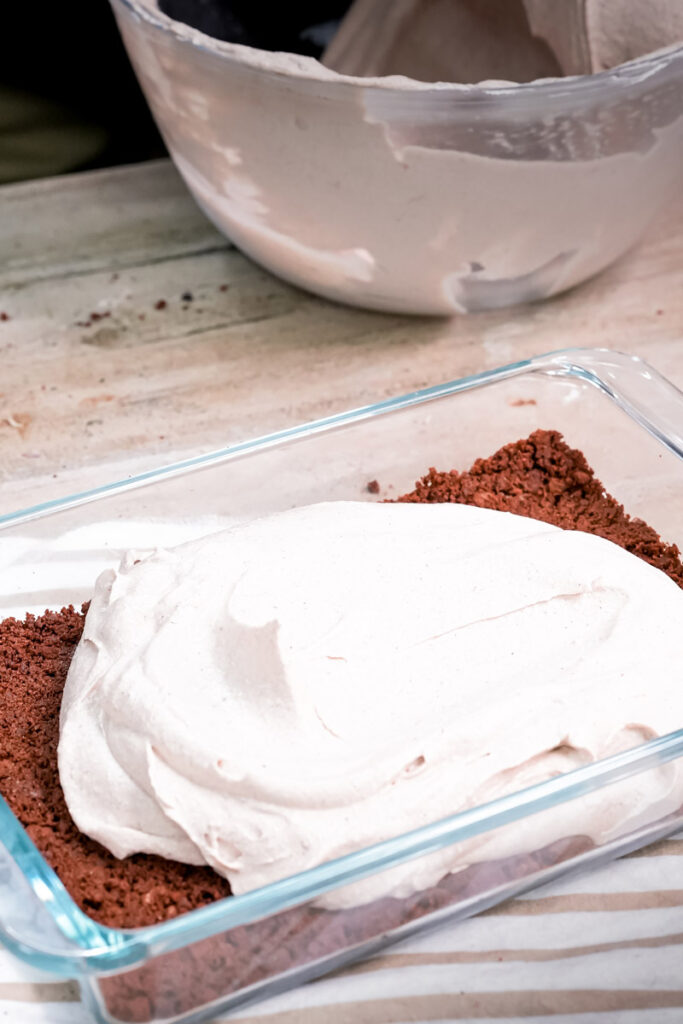Spreading cream cheese layer for Oreo dirt cake