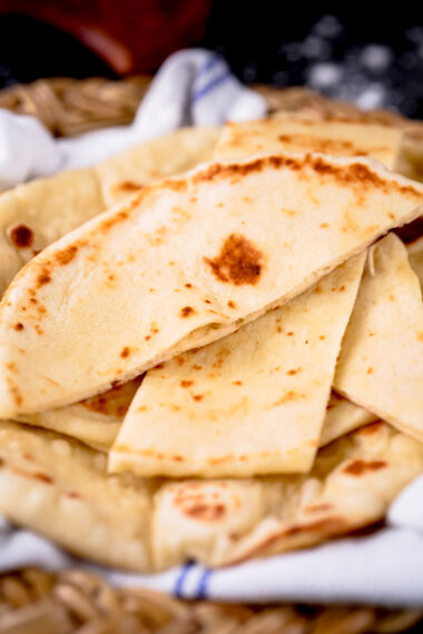 Homemade vegan naan triangles stacked in a basket