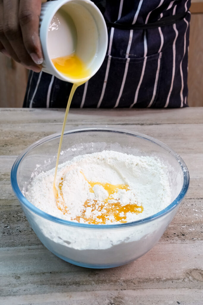 Adding beaten eggs to flour for empanada dough