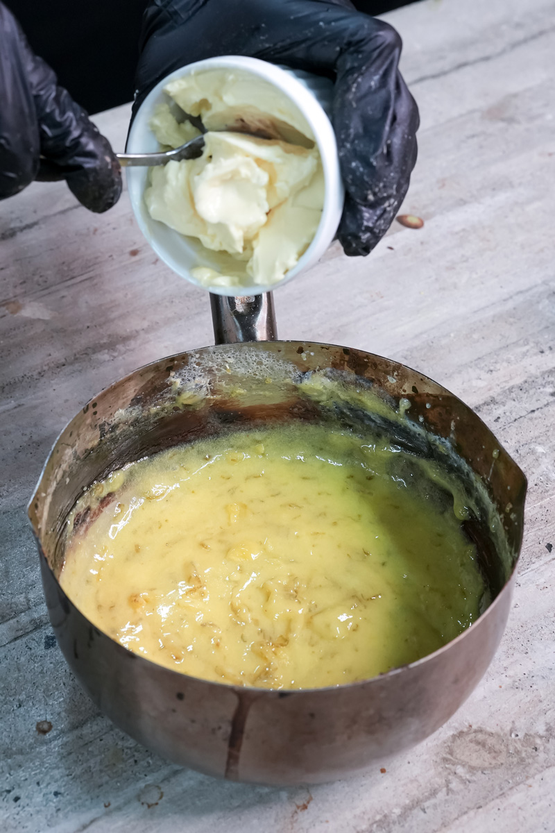 Adding butter to lemon curd mixture in saucepan