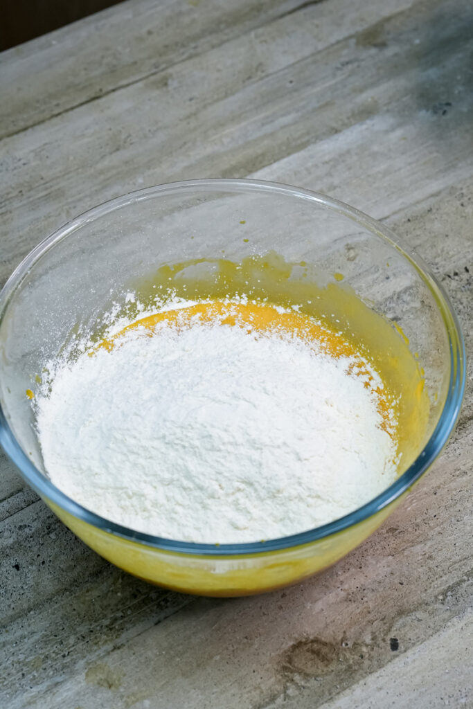 Adding flour to mango muffin batter mixture
