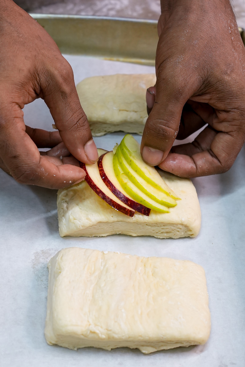 Adding fresh apple slices to Danish pastry dough