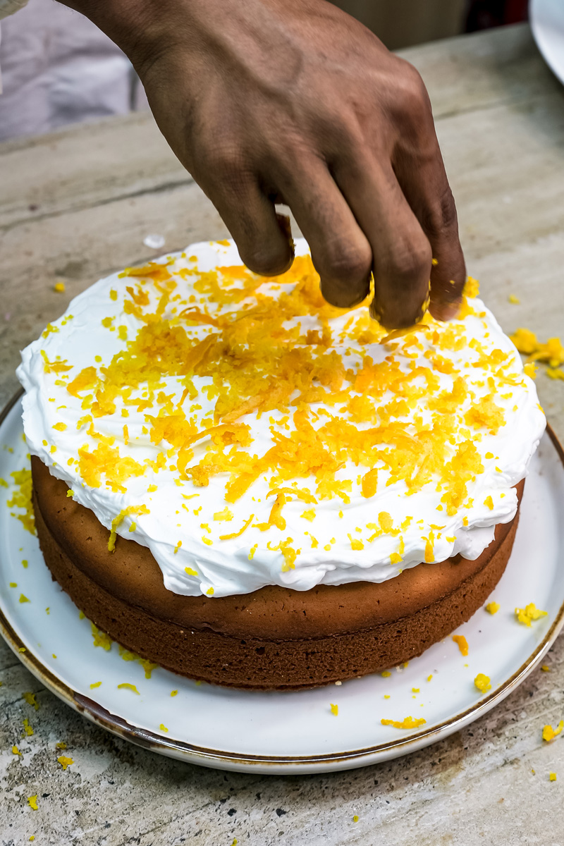 Adding fresh orange zest to citrus cake frosting