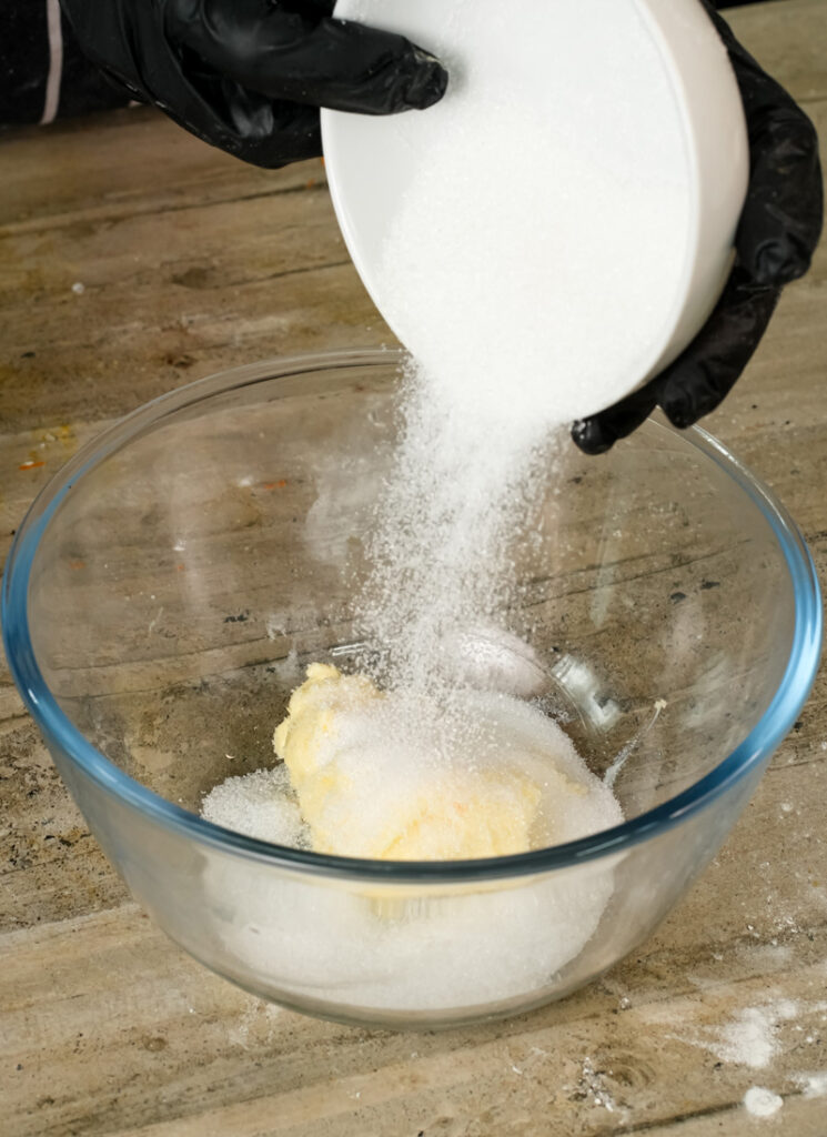 Adding sugar to cinnamon roll pancake ingredients in mixing bowl