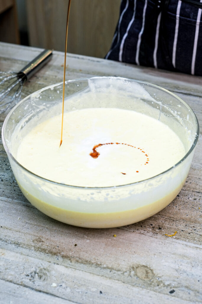 Adding vanilla extract to churro cake batter with whisk