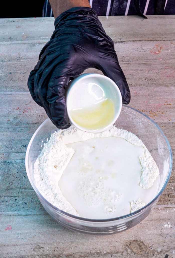 Adding wet ingredients to flour for homemade cinnamon roll pancakes