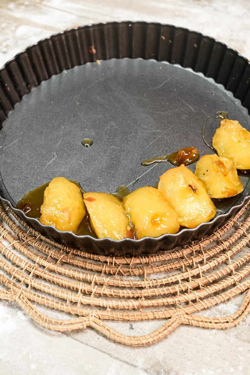 Apple slices arranged in caramel in black tart pan