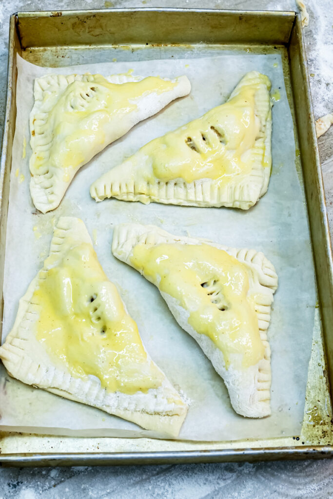 Apple turnovers with egg wash on baking sheet