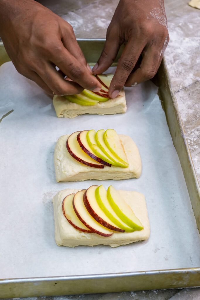 Arranging apple slices on Danish pastry dough rectangles