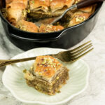 Baklava dessert portion on white plate with gold fork