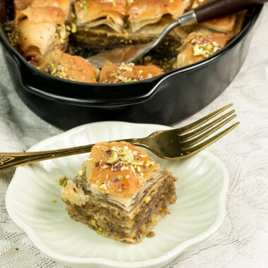 Baklava dessert portion on white plate with gold fork