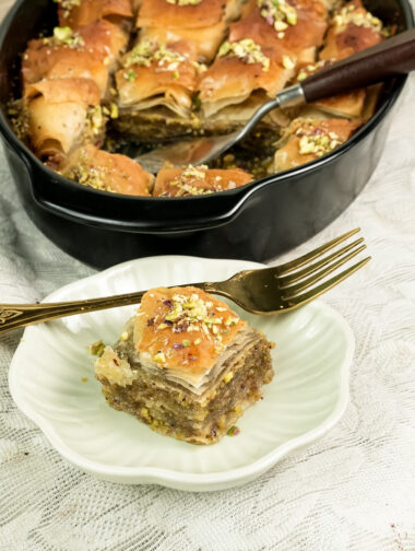 Baklava dessert portion on white plate with gold fork