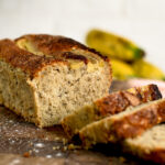 Sliced banana pound cake with golden brown crust and moist crumb on wooden cutting board