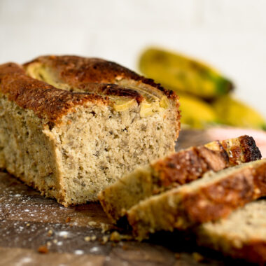 Sliced banana pound cake with golden brown crust and moist crumb on wooden cutting board