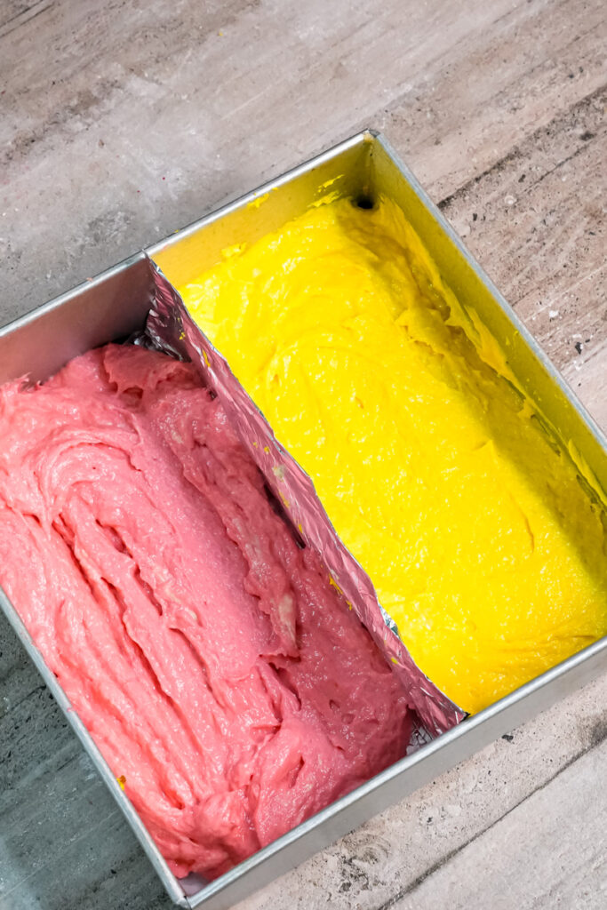 Battenberg cake batter in pan showing pink and yellow sections