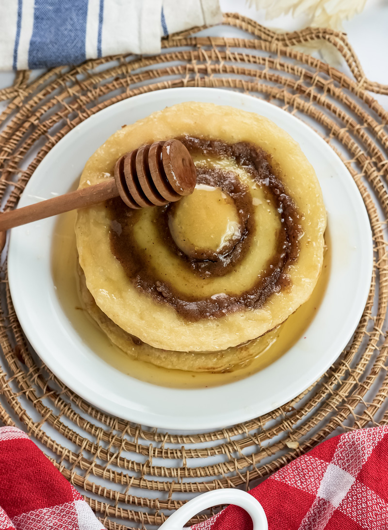 Breakfast cinnamon roll pancakes with honey dipper on wicker placemat