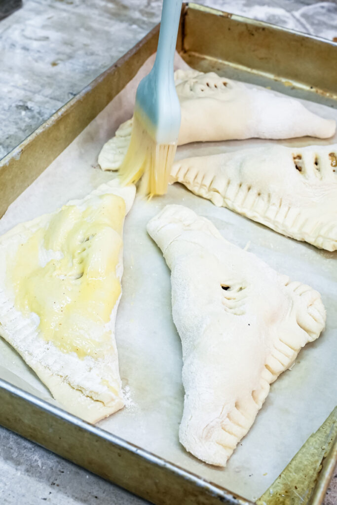 Brushing apple turnovers with egg wash before baking