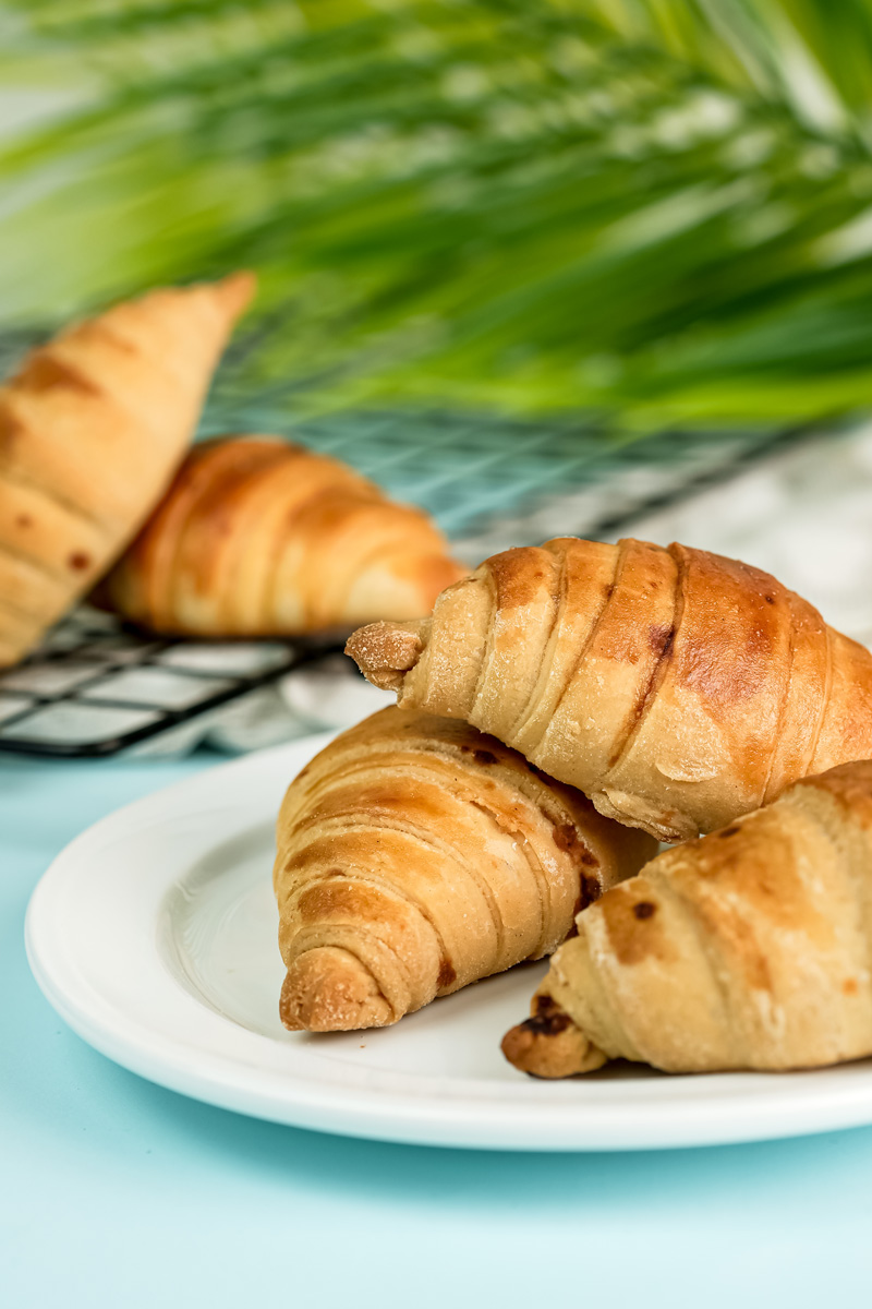 Buttery croissant bread with dried fruit on white plate