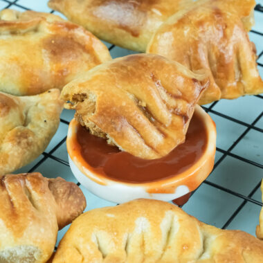 Adding sauce to chicken empanada filling