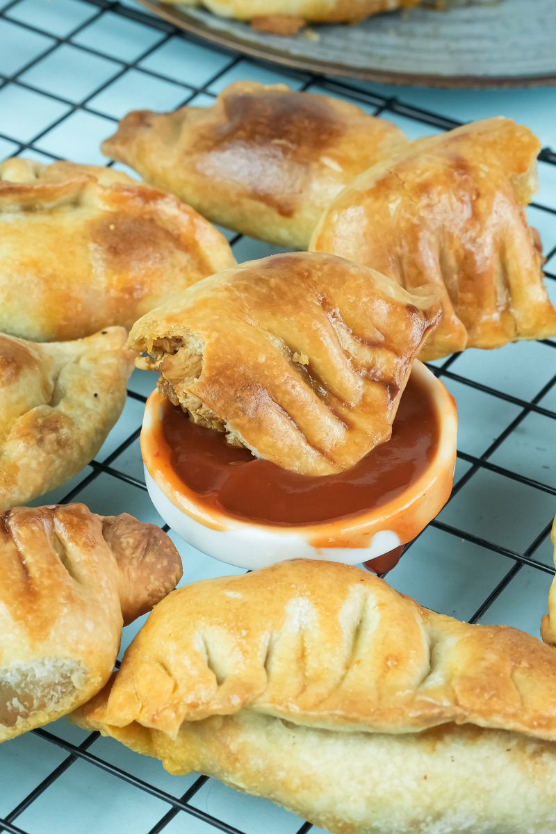 Adding sauce to chicken empanada filling