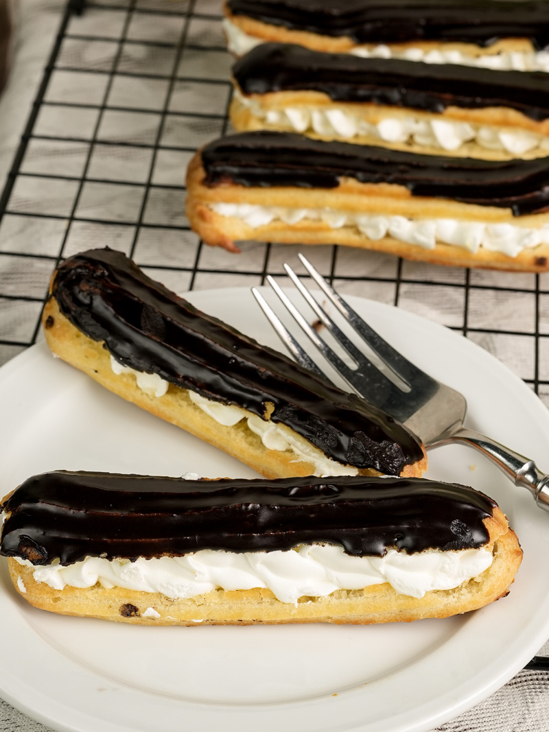 Chocolate eclair with cream filling on plate with dessert fork