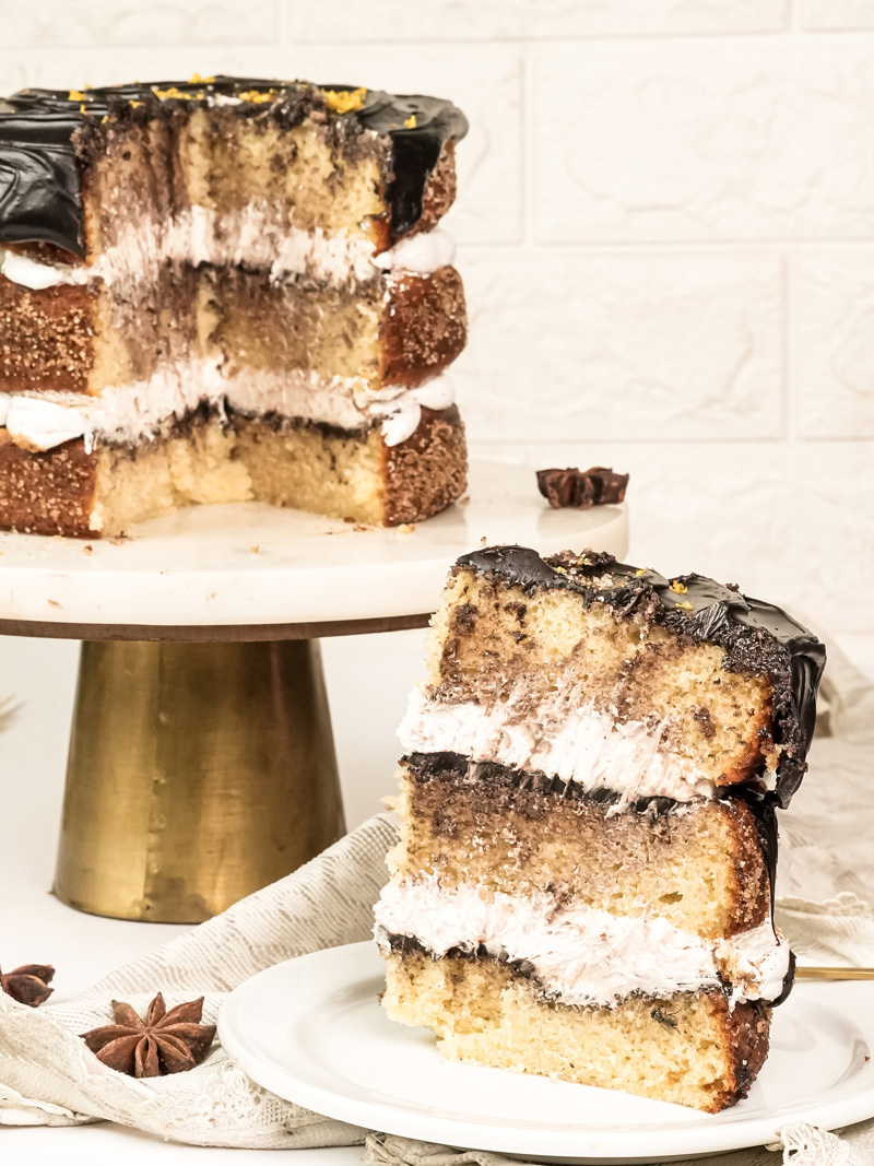 Churro cake slice showing layers of sponge, cream filling and chocolate ganache
