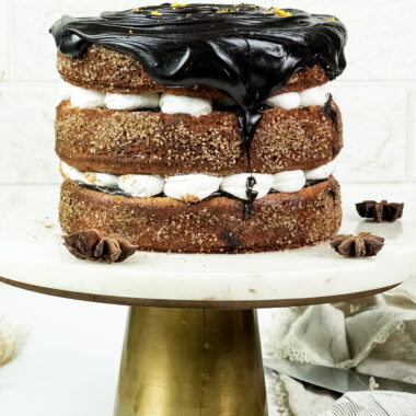 Churro cake with chocolate ganache drip and cinnamon sugar layers on gold cake stand