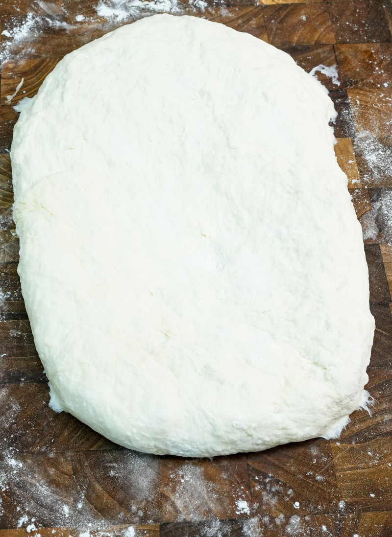 Ciabatta dough shaped into oval on floured surface