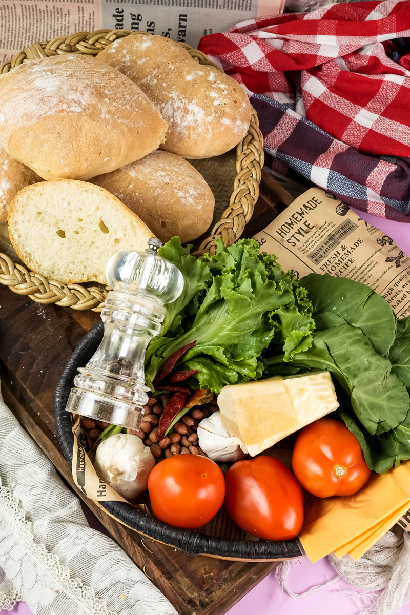 Ciabatta sandwich ingredients in rustic basket with vegetables and cheese