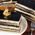 Classic opera cake slice on white plate with gold leaf decoration