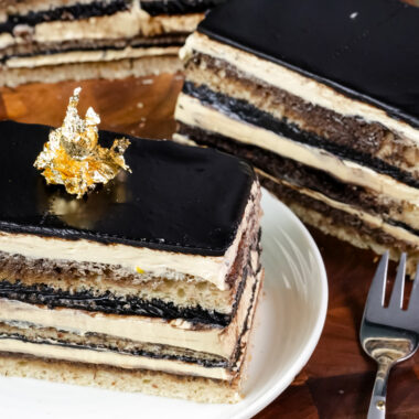 Classic opera cake slice on white plate with gold leaf decoration