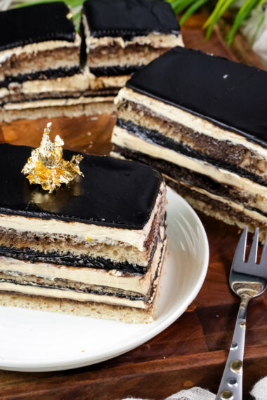 Classic opera cake slice on white plate with gold leaf decoration