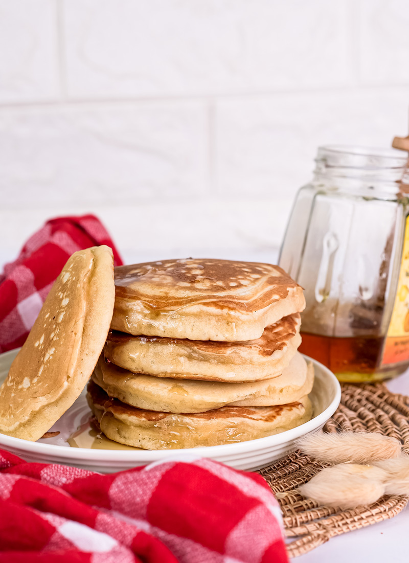 Close-up of gluten free pancake stack with honey jar and wicker placemat