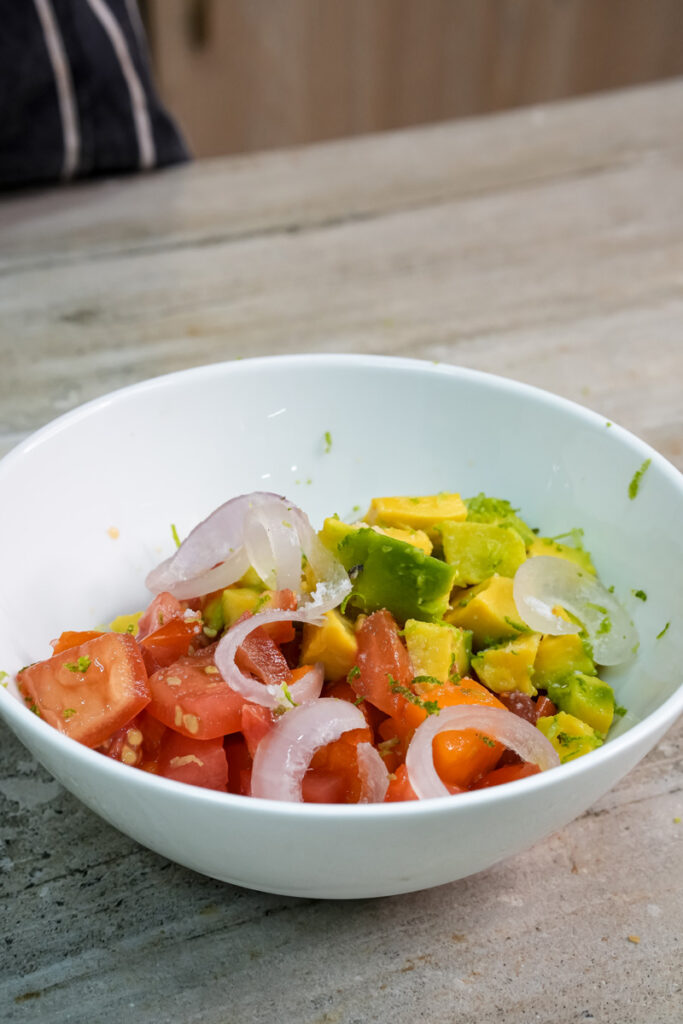 Colorful mango avocado salad ingredients mixed in serving bowl