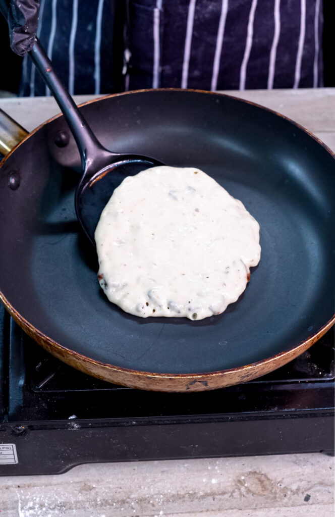 Cooking Oreo pancake in pan showing bubbles forming
